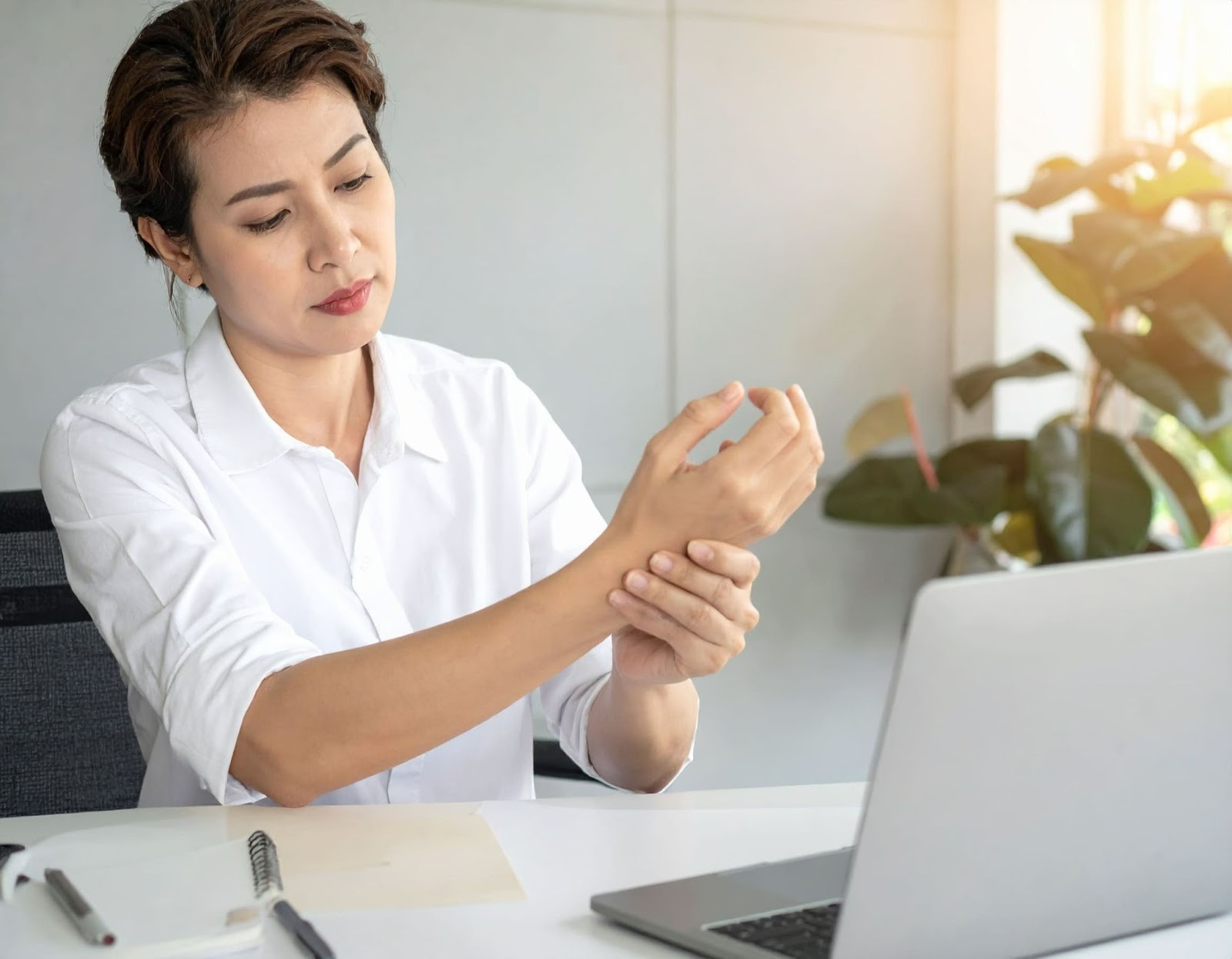 女性在辦公桌前揉著手腕，露出疲勞表情